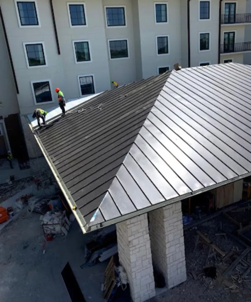 Crew installing standing seam metal roof panels on a commercial project in Derby